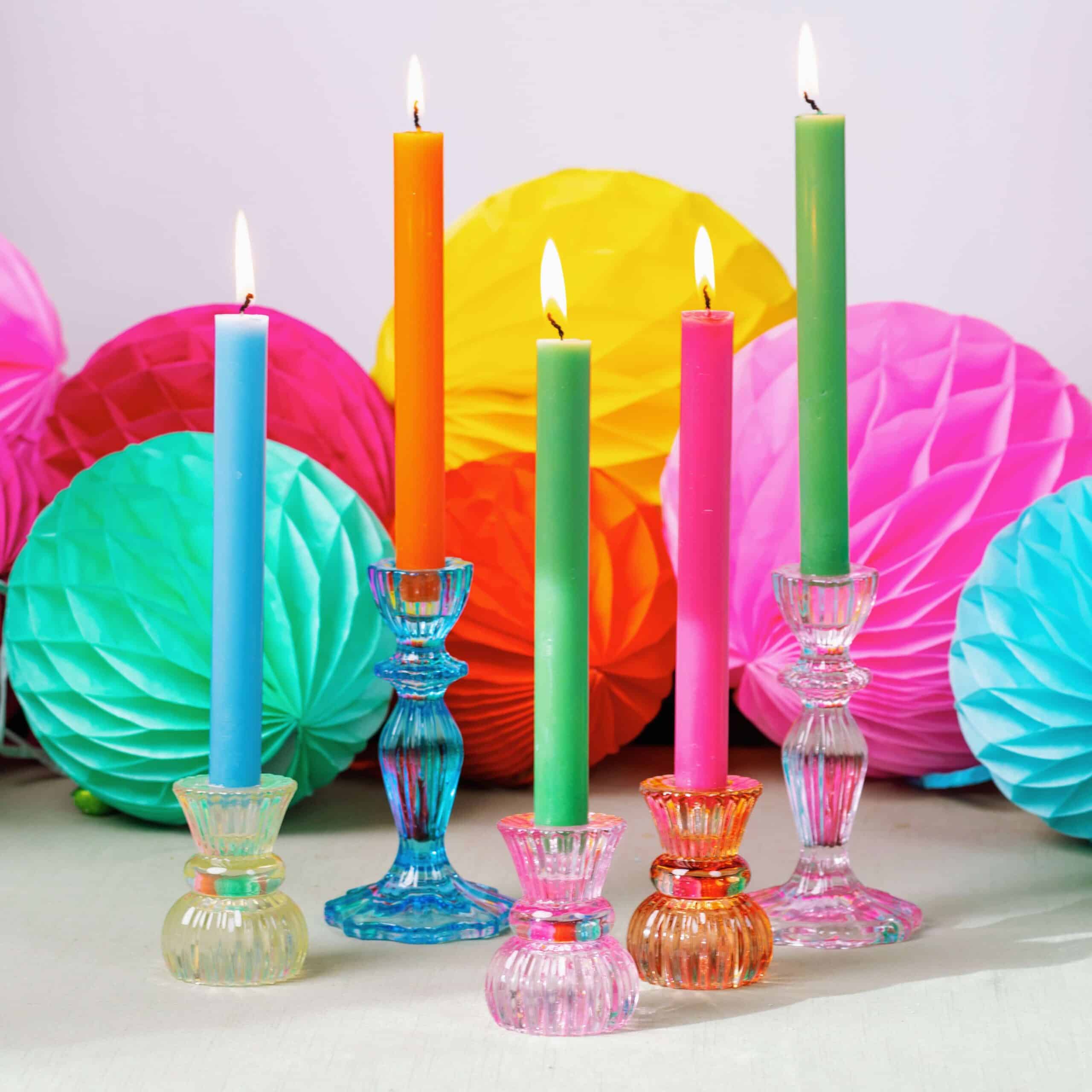 Colourful glass candlesticks with paper lanterns behind